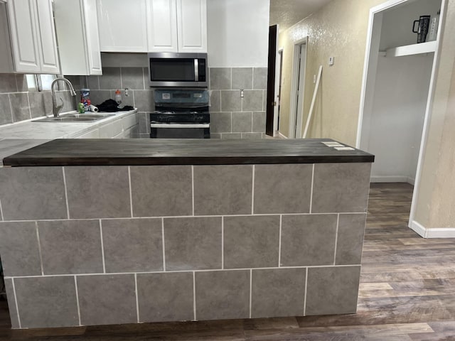714 Locust St, Clayton, NM 88415 - kitchen featuring stainless steel appliances, dark wood finished floors, white cabinetry, and tasteful backsplash