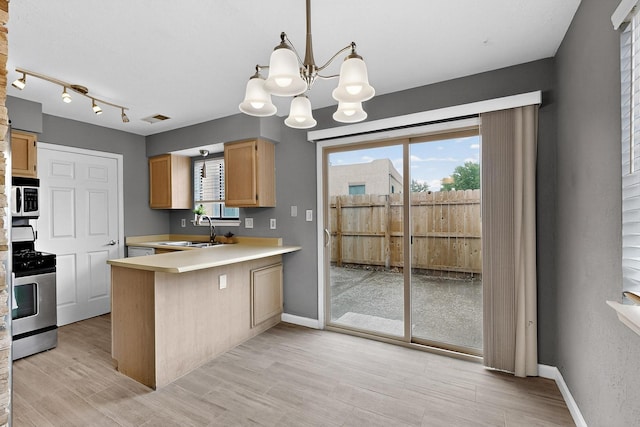 2900 Vista Del Rey NE Unit 7A, Albuquerque, NM 87112 - kitchen featuring gas stove, a chandelier, healthy amount of natural light, and a peninsula