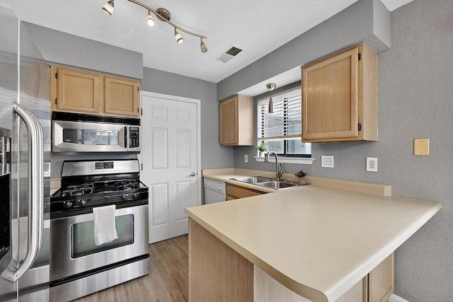 2900 Vista Del Rey NE Unit 7A, Albuquerque, NM 87112 - kitchen featuring appliances with stainless steel finishes, a peninsula, light brown cabinets, light countertops, and a textured wall