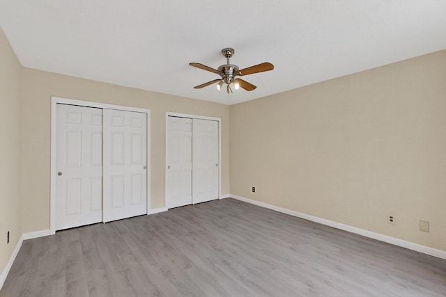 2900 Vista Del Rey NE Unit 7A, Albuquerque, NM 87112 - unfurnished bedroom featuring two closets, wood finished floors, and ceiling fan
