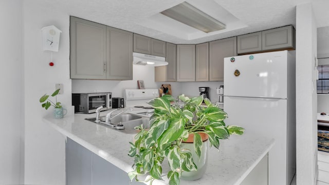 6041 Sequoia Rd NW Unit B3, Albuquerque, NM 87120 - kitchen with white appliances, gray cabinetry, under cabinet range hood, and a peninsula