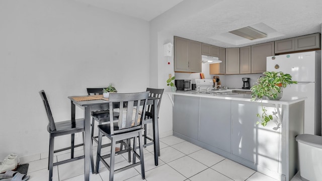 6041 Sequoia Rd NW Unit B3, Albuquerque, NM 87120 - kitchen with light countertops, a peninsula, under cabinet range hood, light tile patterned flooring, and stainless steel microwave