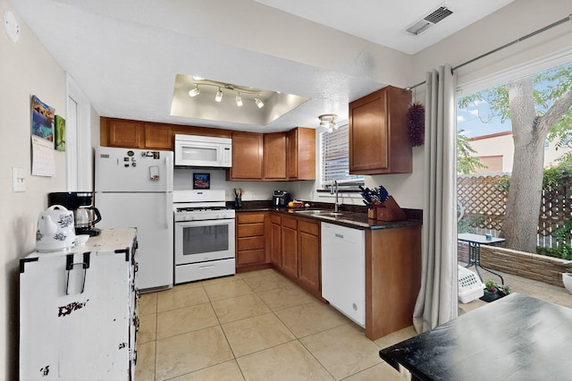 700 Fruit Ave NW Unit G, Albuquerque, NM 87102 - kitchen with white appliances, a raised ceiling, light tile patterned flooring, brown cabinets, and dark countertops