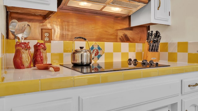 13101 Comanche Rd NE, Albuquerque, NM 87111 - kitchen view of backsplash, exhaust hood, white cabinetry, and tile counters