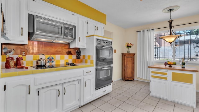 13101 Comanche Rd NE, Albuquerque, NM 87111 - kitchen with black appliances, tile counters, white cabinets, backsplash, and pendant lighting