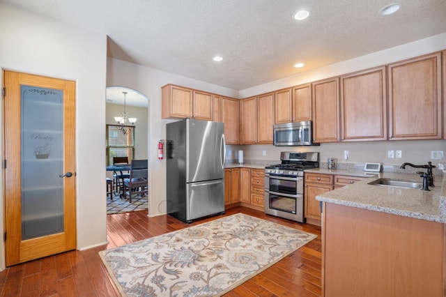 6615 Mountain Hawk Loop NE, Rio Rancho, NM 87144 - kitchen with stainless steel appliances, light stone counters, a chandelier, dark wood-style floors, and recessed lighting