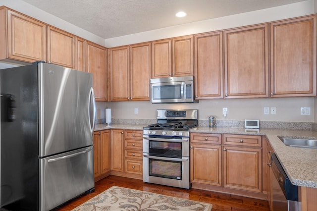6615 Mountain Hawk Loop NE, Rio Rancho, NM 87144 - kitchen featuring appliances with stainless steel finishes, dark wood-style floors, recessed lighting, light stone countertops, and brown cabinetry