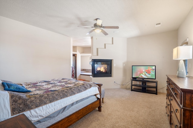6615 Mountain Hawk Loop NE, Rio Rancho, NM 87144 - bedroom featuring a multi sided fireplace, light colored carpet, and a ceiling fan