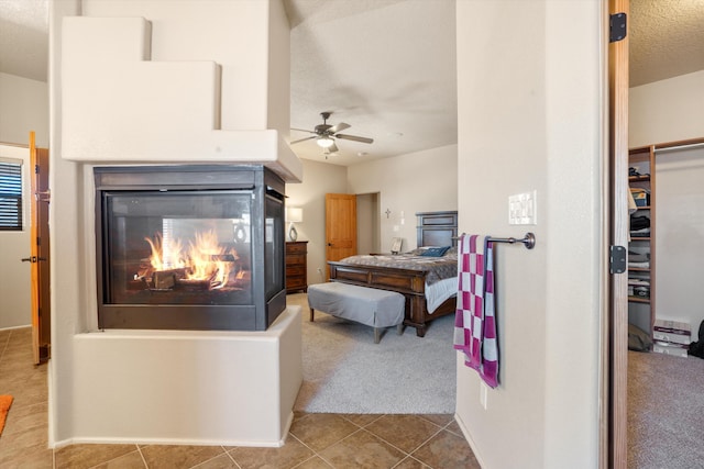 6615 Mountain Hawk Loop NE, Rio Rancho, NM 87144 - carpeted bedroom featuring a multi sided fireplace, tile patterned flooring, a textured ceiling, a closet, and a ceiling fan