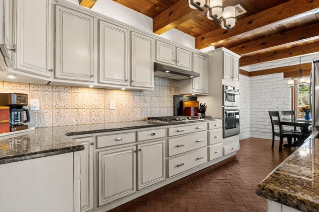 1524 W Meadowlark Ln, Corrales, NM 87048 - kitchen featuring under cabinet range hood, a wood ceiling with exposed beams, appliances with stainless steel finishes, brick flooring, and brick wall
