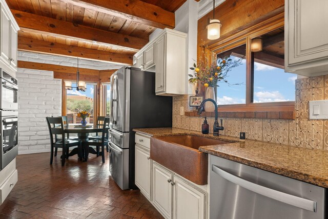 1524 W Meadowlark Ln, Corrales, NM 87048 - kitchen featuring appliances with stainless steel finishes, a wooden ceiling with exposed beams, backsplash, brick flooring, and dark stone counters