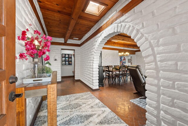 1524 W Meadowlark Ln, Corrales, NM 87048 - entryway with a wooden ceiling with exposed beams, a chandelier, brick flooring, arched walkways, and brick wall