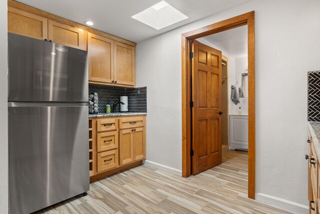1524 W Meadowlark Ln, Corrales, NM 87048 - kitchen featuring freestanding refrigerator, a skylight, backsplash, and light wood-style flooring