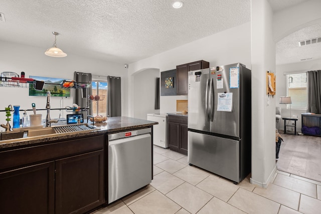 9909 Saddlehorn Trl SW, Albuquerque, NM 87121 - kitchen with stainless steel appliances, arched walkways, a textured ceiling, dark brown cabinets, and healthy amount of natural light