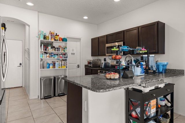 9909 Saddlehorn Trl SW, Albuquerque, NM 87121 - kitchen featuring stainless steel appliances, arched walkways, dark brown cabinets, a peninsula, and light tile patterned floors