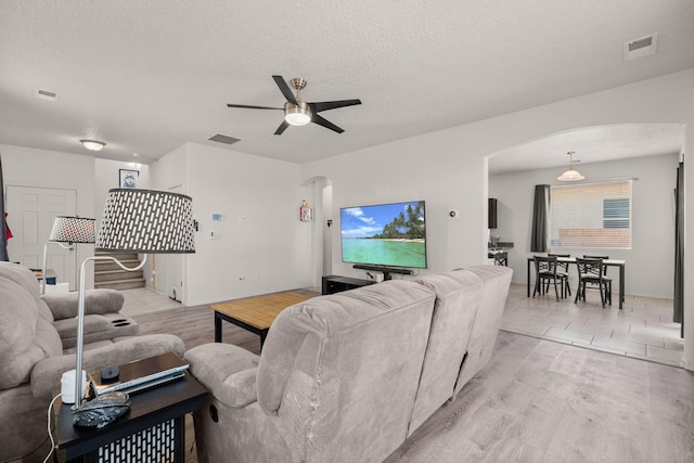 9909 Saddlehorn Trl SW, Albuquerque, NM 87121 - living area with arched walkways, a ceiling fan, light wood-style flooring, and a textured ceiling