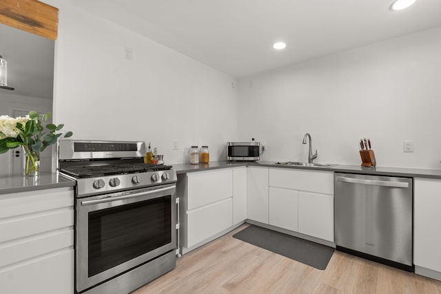 11608 Clifford Ave NE, Albuquerque, NM 87112 - kitchen featuring appliances with stainless steel finishes, white cabinets, recessed lighting, light wood-style flooring, and dark countertops