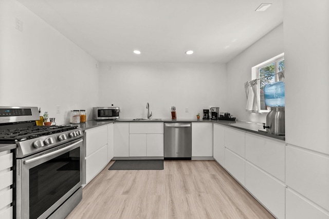 11608 Clifford Ave NE, Albuquerque, NM 87112 - kitchen with appliances with stainless steel finishes, white cabinets, light wood-style flooring, recessed lighting, and dark countertops