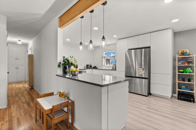 11608 Clifford Ave NE, Albuquerque, NM 87112 - kitchen with freestanding refrigerator, light wood-style flooring, white cabinets, dark countertops, and a peninsula