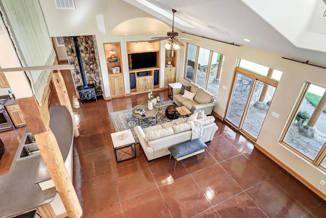 276 Trosello Ln, Corrales, NM 87048 - living room featuring a wood stove, built in shelves, a ceiling fan, high vaulted ceiling, and dark tile patterned flooring