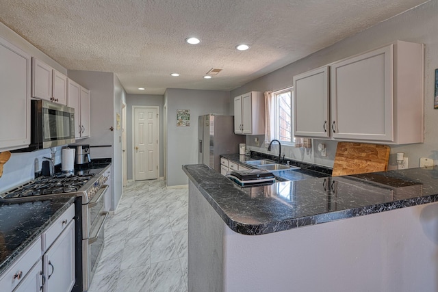 10405 Red Robin Rd SW, Albuquerque, NM 87121 - kitchen with appliances with stainless steel finishes, dark stone counters, light marble finish flooring, a peninsula, and recessed lighting