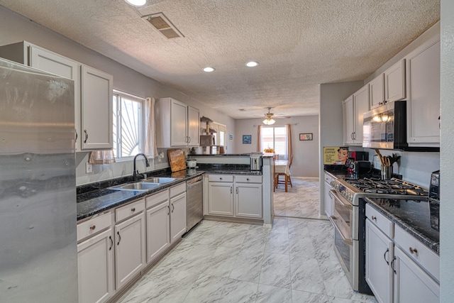 10405 Red Robin Rd SW, Albuquerque, NM 87121 - kitchen with stainless steel appliances, a peninsula, a ceiling fan, light marble finish floors, and a textured ceiling