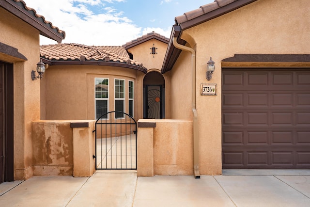 3726 Linda Vista Ave NE, Rio Rancho, NM 87124 - doorway to property featuring stucco siding, concrete driveway, a gate, and a tiled roof