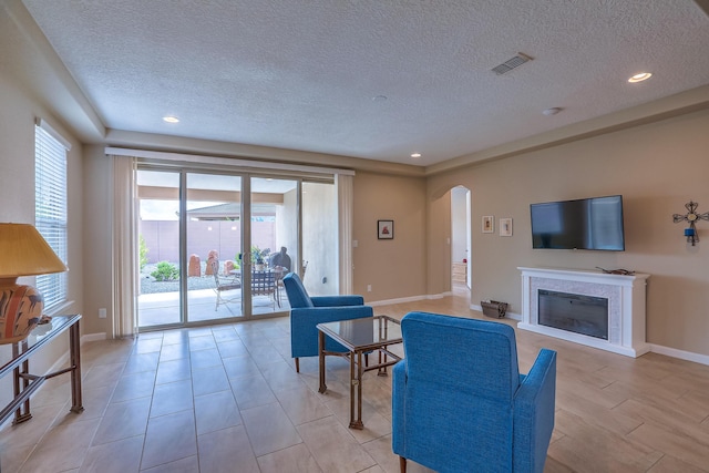 2952 Kings Canyon Loop NE, Rio Rancho, NM 87144 - living room with a textured ceiling, arched walkways, a glass covered fireplace, and recessed lighting