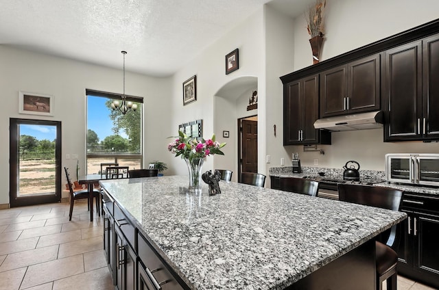 76 Otero Rd, Los Lunas, NM 87031 - kitchen featuring under cabinet range hood, a center island, light stone countertops, a chandelier, and a textured ceiling