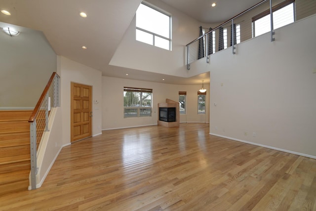315 11th St SW, Albuquerque, NM 87102 - unfurnished living room featuring stairs, a high ceiling, recessed lighting, and light wood-style flooring