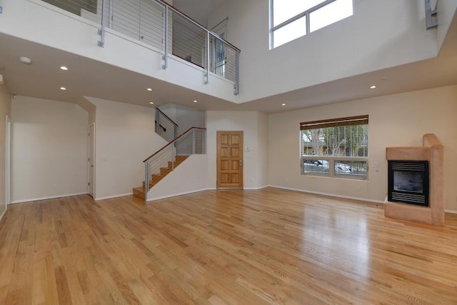 315 11th St SW, Albuquerque, NM 87102 - unfurnished living room with a multi sided fireplace, light wood finished floors, a towering ceiling, stairway, and recessed lighting