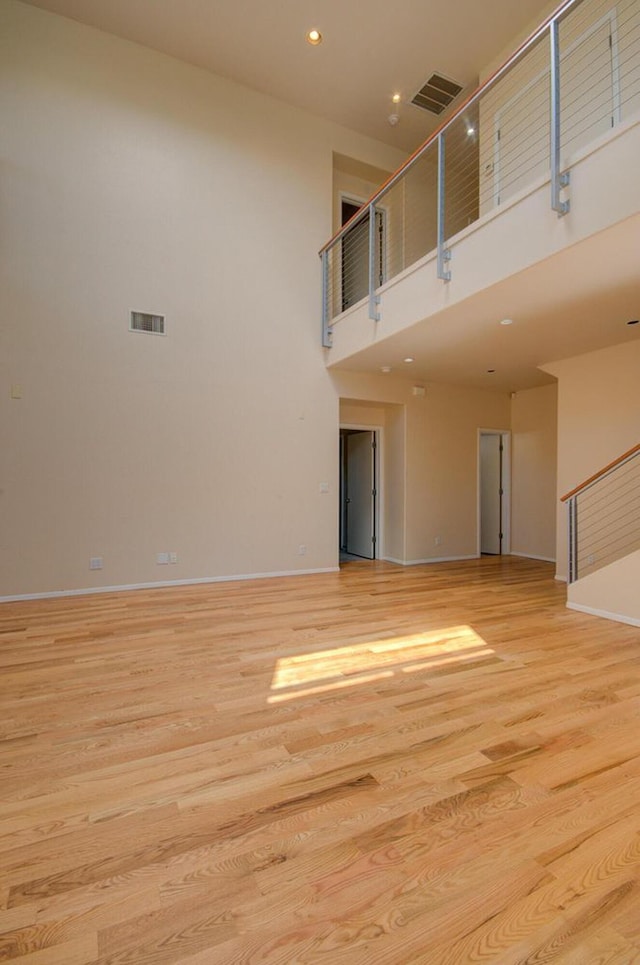 315 11th St SW, Albuquerque, NM 87102 - unfurnished living room with a towering ceiling, light wood-style floors, recessed lighting, and stairway