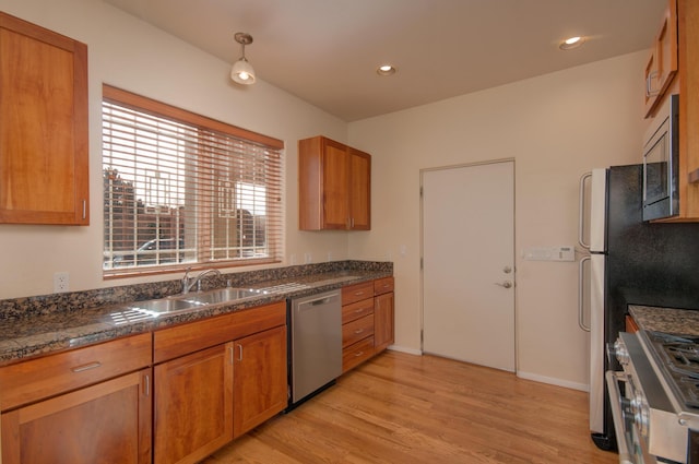 315 11th St SW, Albuquerque, NM 87102 - kitchen featuring stainless steel appliances, brown cabinetry, light wood-style floors, and dark countertops