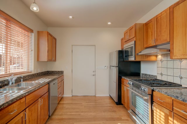 315 11th St SW, Albuquerque, NM 87102 - kitchen with appliances with stainless steel finishes, under cabinet range hood, tasteful backsplash, light wood finished floors, and brown cabinetry