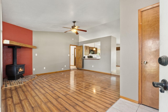 36 Palomas Rd, Los Lunas, NM 87031 - unfurnished living room featuring ceiling fan, wood finished floors, vaulted ceiling, and a wood stove