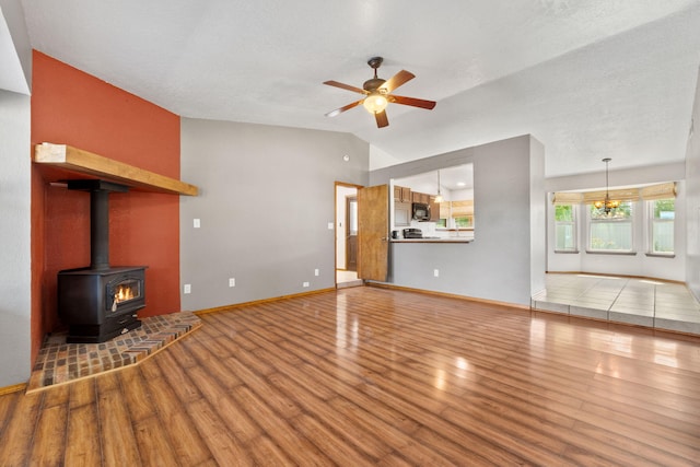 36 Palomas Rd, Los Lunas, NM 87031 - unfurnished living room featuring lofted ceiling, wood finished floors, ceiling fan, and a wood stove