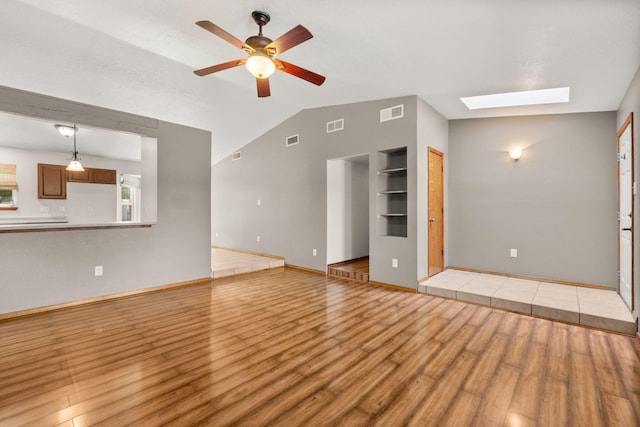 36 Palomas Rd, Los Lunas, NM 87031 - unfurnished living room with light wood-type flooring, lofted ceiling, ceiling fan, a skylight, and built in shelves