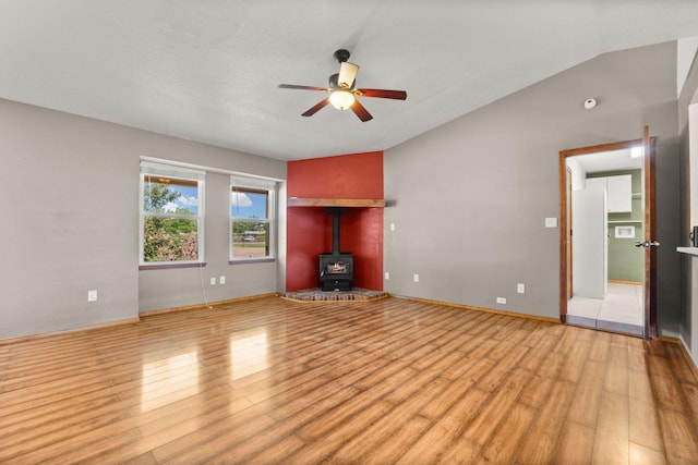 36 Palomas Rd, Los Lunas, NM 87031 - unfurnished living room with light wood-style floors, vaulted ceiling, a ceiling fan, and a wood stove