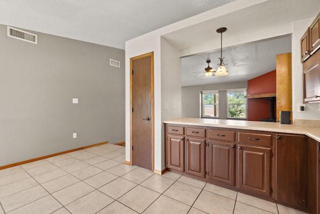 36 Palomas Rd, Los Lunas, NM 87031 - kitchen with light countertops, ceiling fan, decorative light fixtures, light tile patterned floors, and brown cabinets
