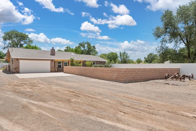 36 Palomas Rd, Los Lunas, NM 87031 - view of front facade with dirt driveway, an attached garage, stone siding, and a chimney