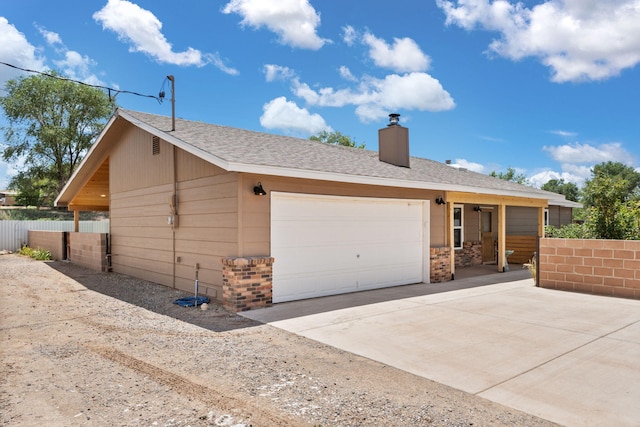 36 Palomas Rd, Los Lunas, NM 87031 - view of front facade with a chimney, concrete driveway, a garage, and roof with shingles