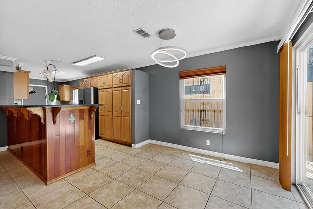 5415 Colleens Way NE, Albuquerque, NM 87111 - kitchen with plenty of natural light, a breakfast bar area, light tile patterned floors, dark countertops, and a textured ceiling