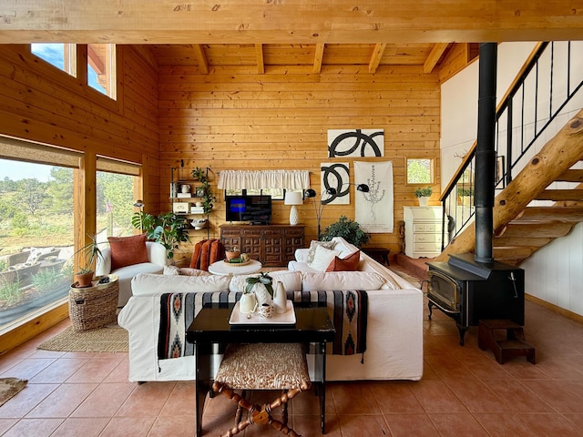 195 Ferguson Rd, Ramah, NM 87321 - tiled living room with a wooden ceiling with exposed beams, wooden walls, a high ceiling, a wood stove, and stairway