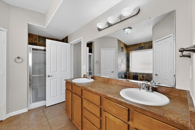 2048 N Ensenada Cir SE, Rio Rancho, NM 87124 - bathroom featuring a shower stall, double vanity, tile patterned flooring, and a textured ceiling