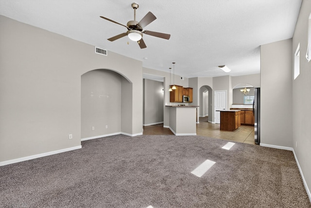2048 N Ensenada Cir SE, Rio Rancho, NM 87124 - unfurnished living room with arched walkways, carpet floors, a ceiling fan, and tile patterned flooring