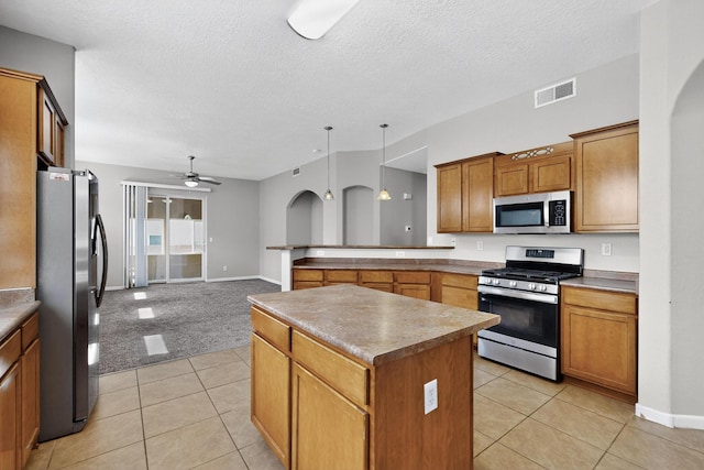 2048 N Ensenada Cir SE, Rio Rancho, NM 87124 - kitchen featuring stainless steel appliances, a ceiling fan, a center island, brown cabinetry, and light tile patterned flooring