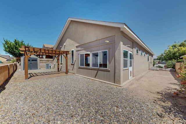 2048 N Ensenada Cir SE, Rio Rancho, NM 87124 - back of property featuring a pergola, a fenced backyard, a storage shed, stucco siding, and a patio