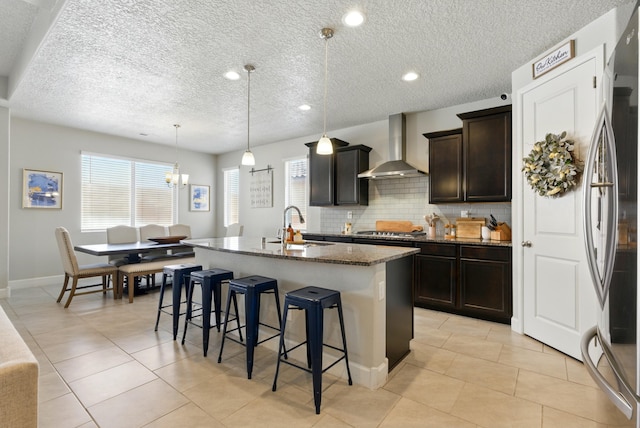 4529 Skyline Loop NE, Rio Rancho, NM 87144 - kitchen featuring wall chimney range hood, dark stone counters, a breakfast bar, an island with sink, and tasteful backsplash