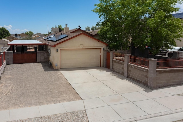 9616 Eucariz Ave SW, Albuquerque, NM 87121 - view of front facade with a garage, concrete driveway, stucco siding, roof mounted solar panels, and a gate