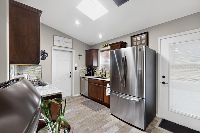 9616 Eucariz Ave SW, Albuquerque, NM 87121 - kitchen with appliances with stainless steel finishes, a skylight, light wood finished floors, backsplash, and lofted ceiling